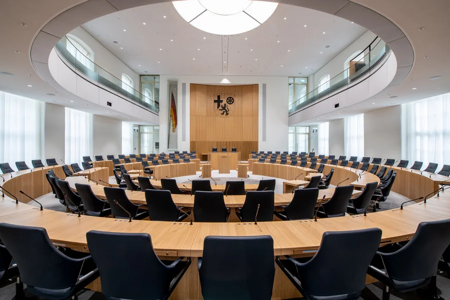 Großer, runder Raum mit vielen Stühlen und Tischen, bekannt als Plenarsaal.